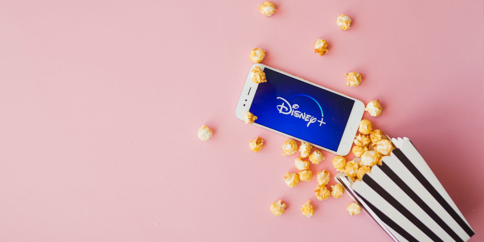 disney logo on phone with box of popcorn on pink background