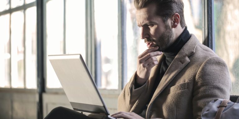 A man is sitting in front of his laptop working on it