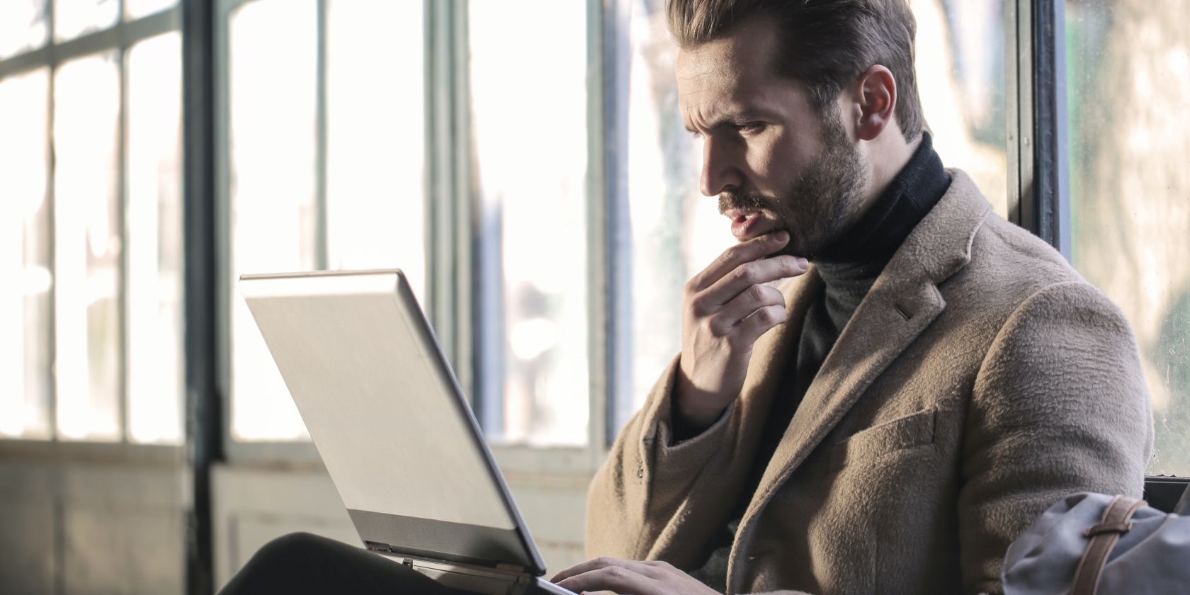 A Man Is Sitting In Front Of His Laptop Working On It.jpg