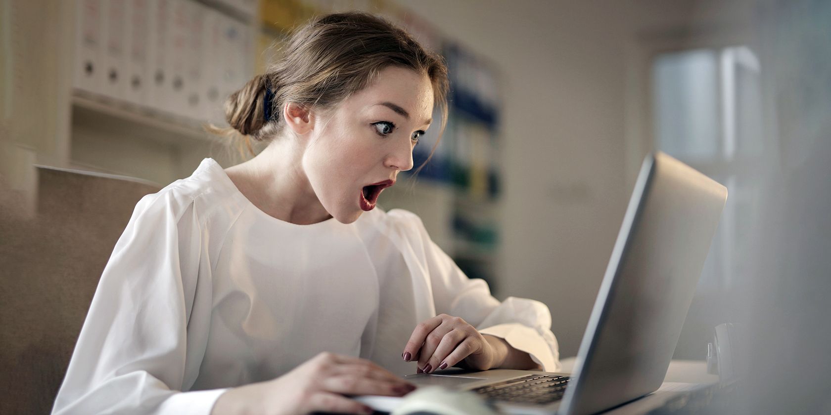 a woman amazed at what s on the computer screen
