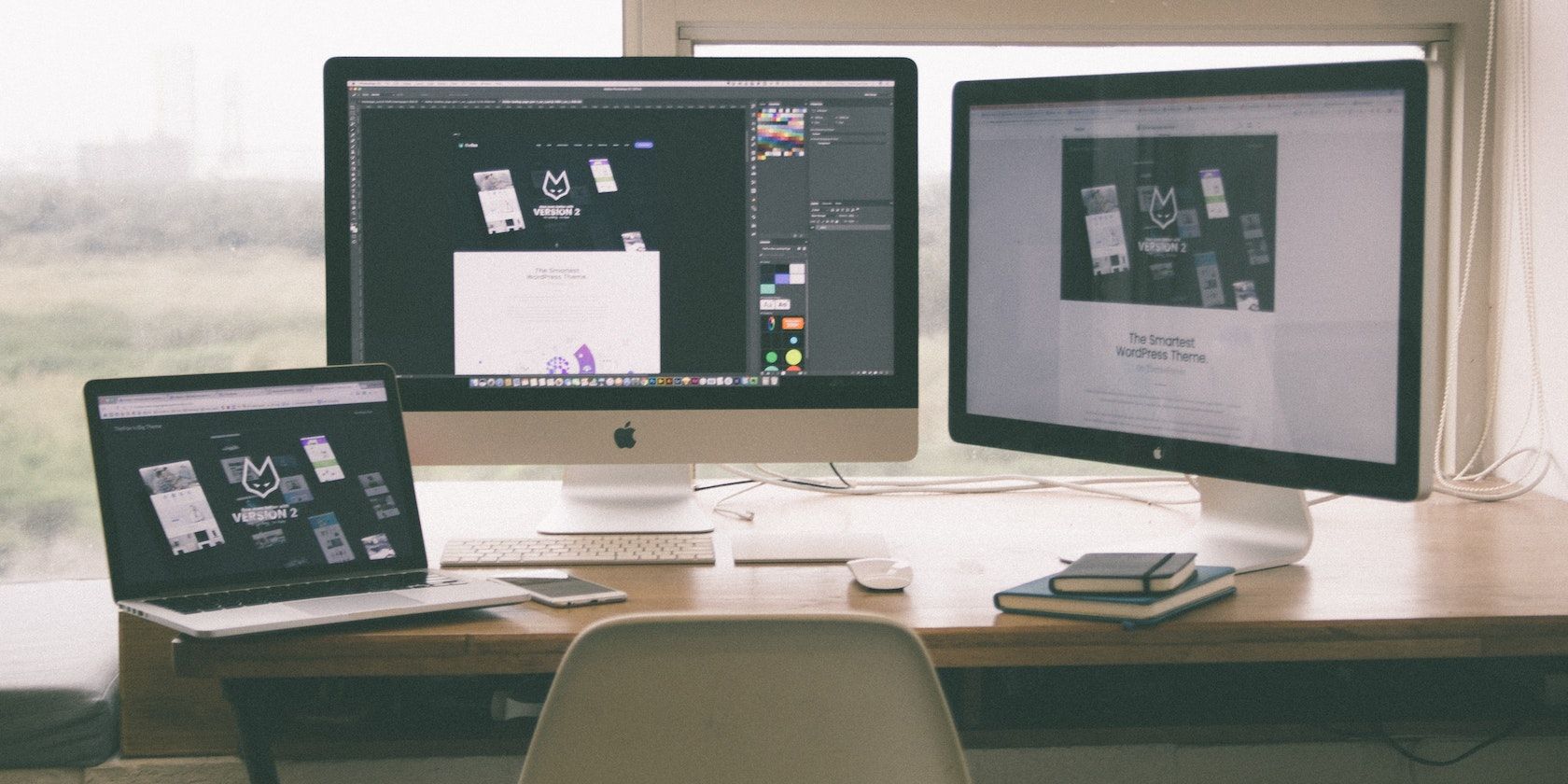 two macs and a macbook on a desk