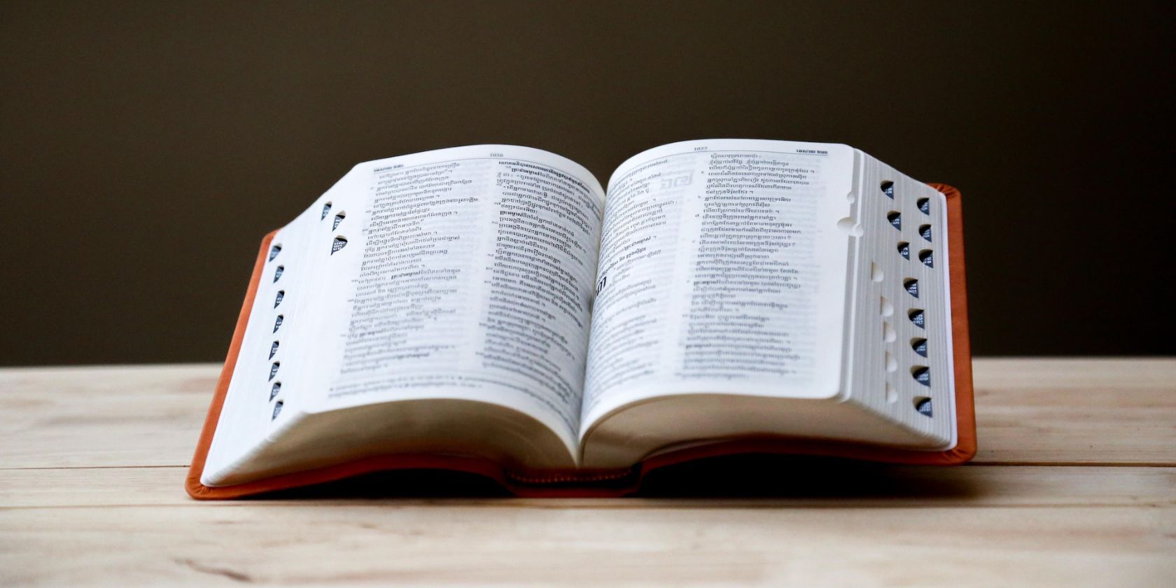 Large dictionary open halfway and propped up on wooden table