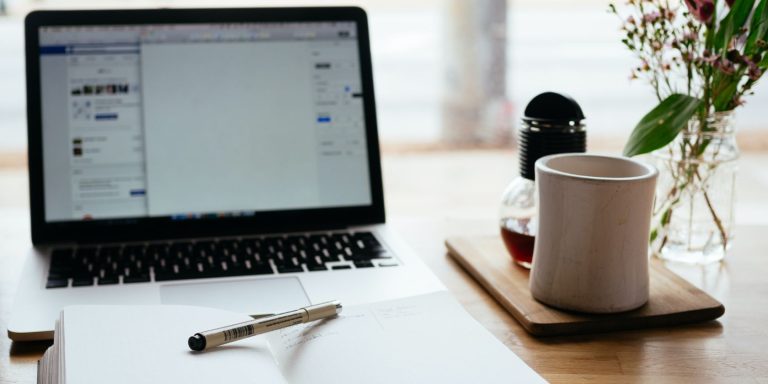 There is a laptop and an open book on the desk