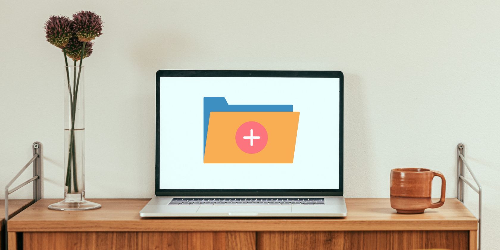 A Laptop With A New Folder Icon On A Wooden Table Near White Wall.jpg