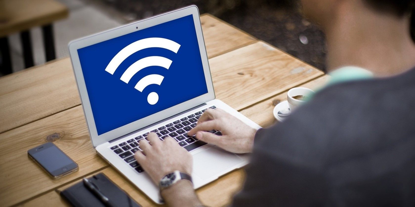 a man using a silver laptop with a wi fi symbol on it