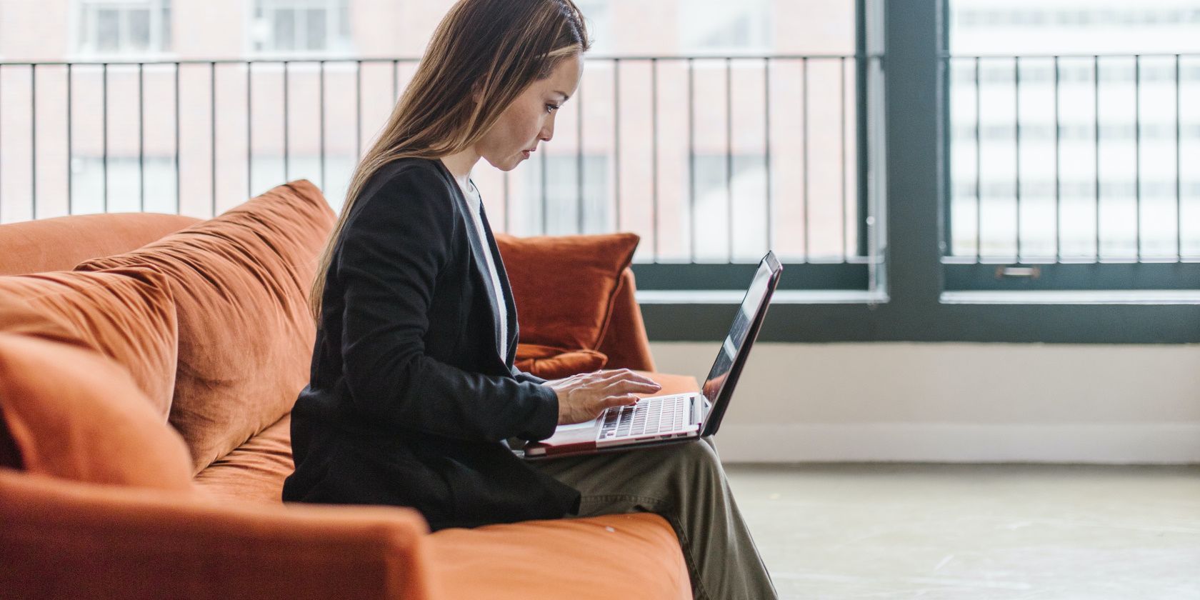 A Woman Using A Laptop While Sitting On A Couch.jpg