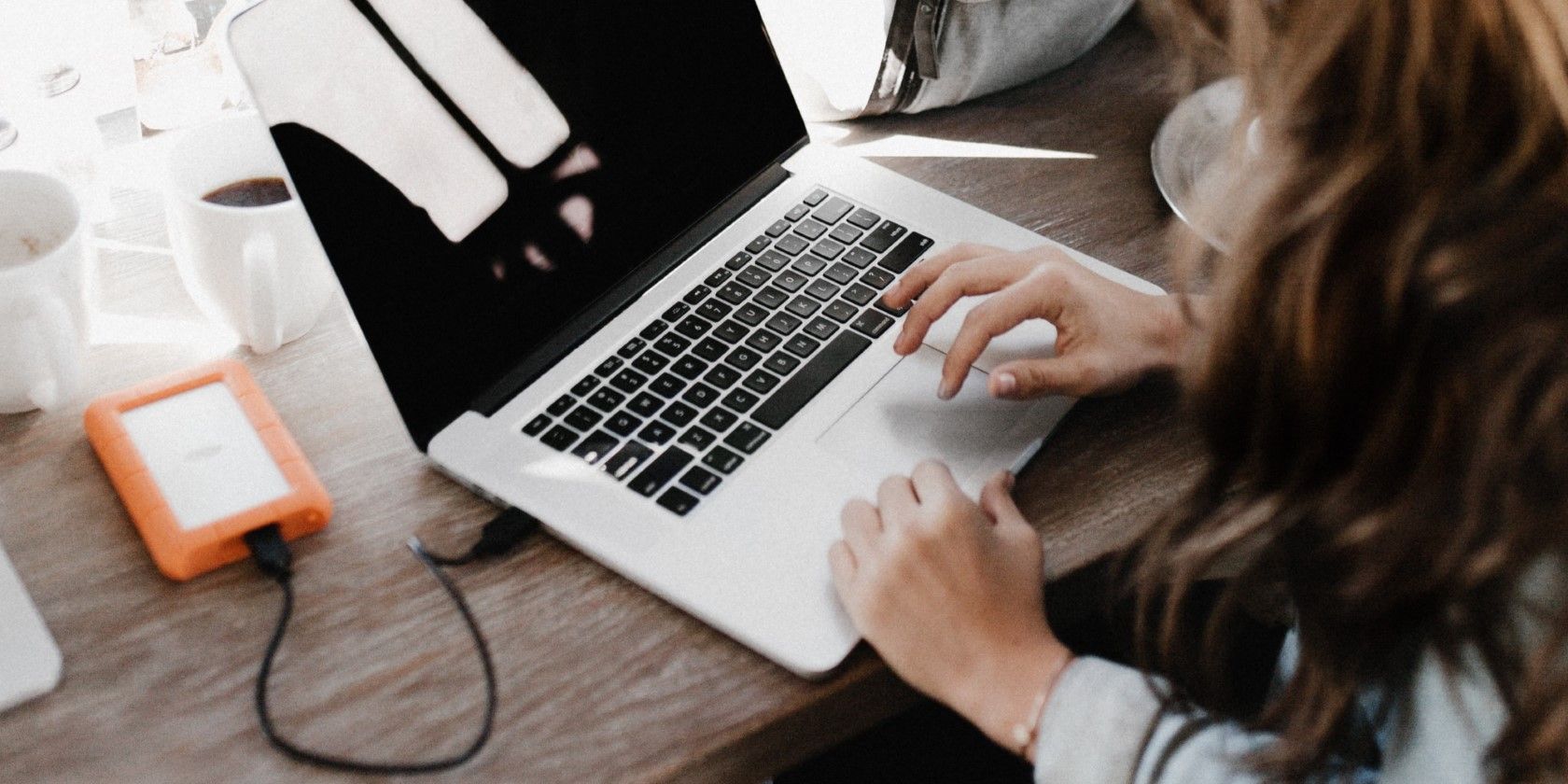 A Woman Working On A Laptop Connected To A Hard Drive.jpg