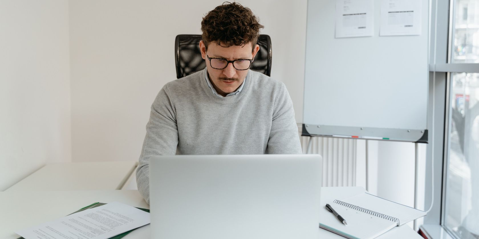 man in gray sweater working on laptop