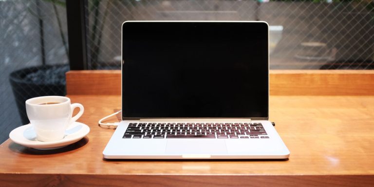 a red table holds a laptop and a cup of tea