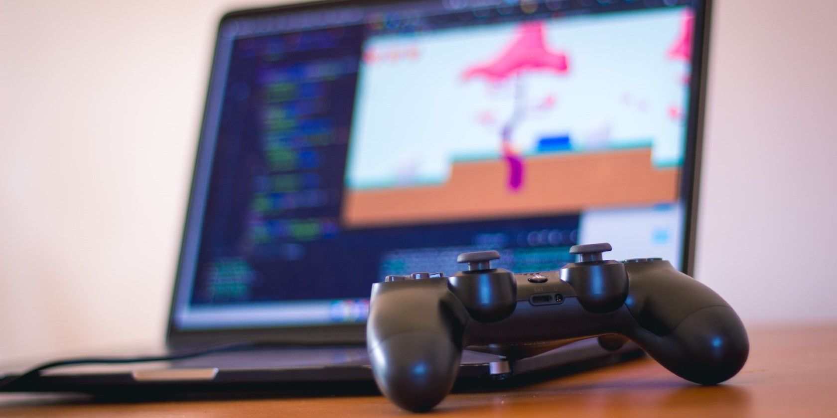 A Laptop And A Gaming Controller On A Wooden Table.jpg