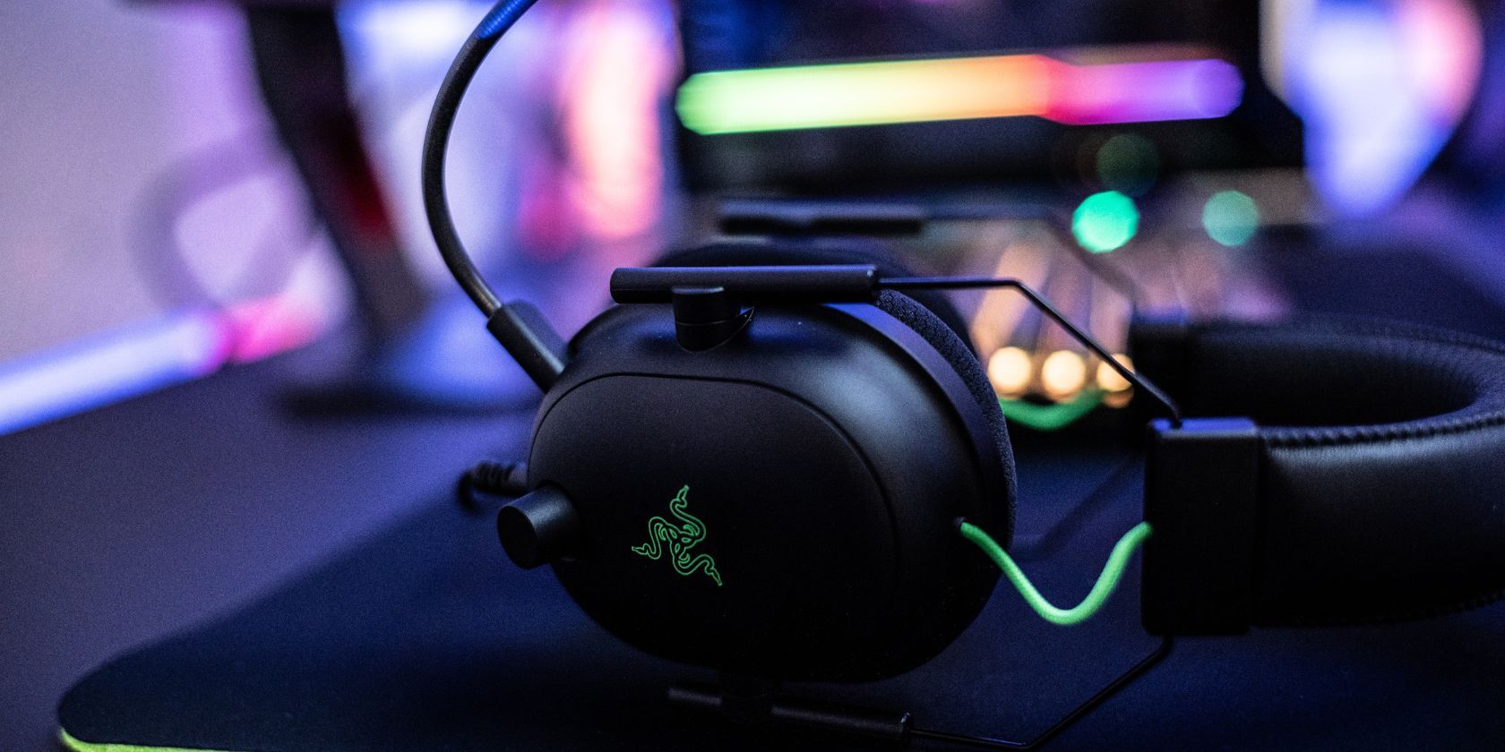 坐在玩家桌上鼠标垫上的绿色和黑色 Razer 耳机