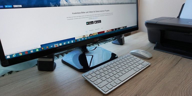 a monitor on a wooden table next to a printer