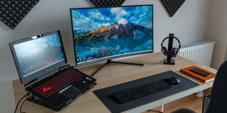 a black laptop and a monitor on a wooden table