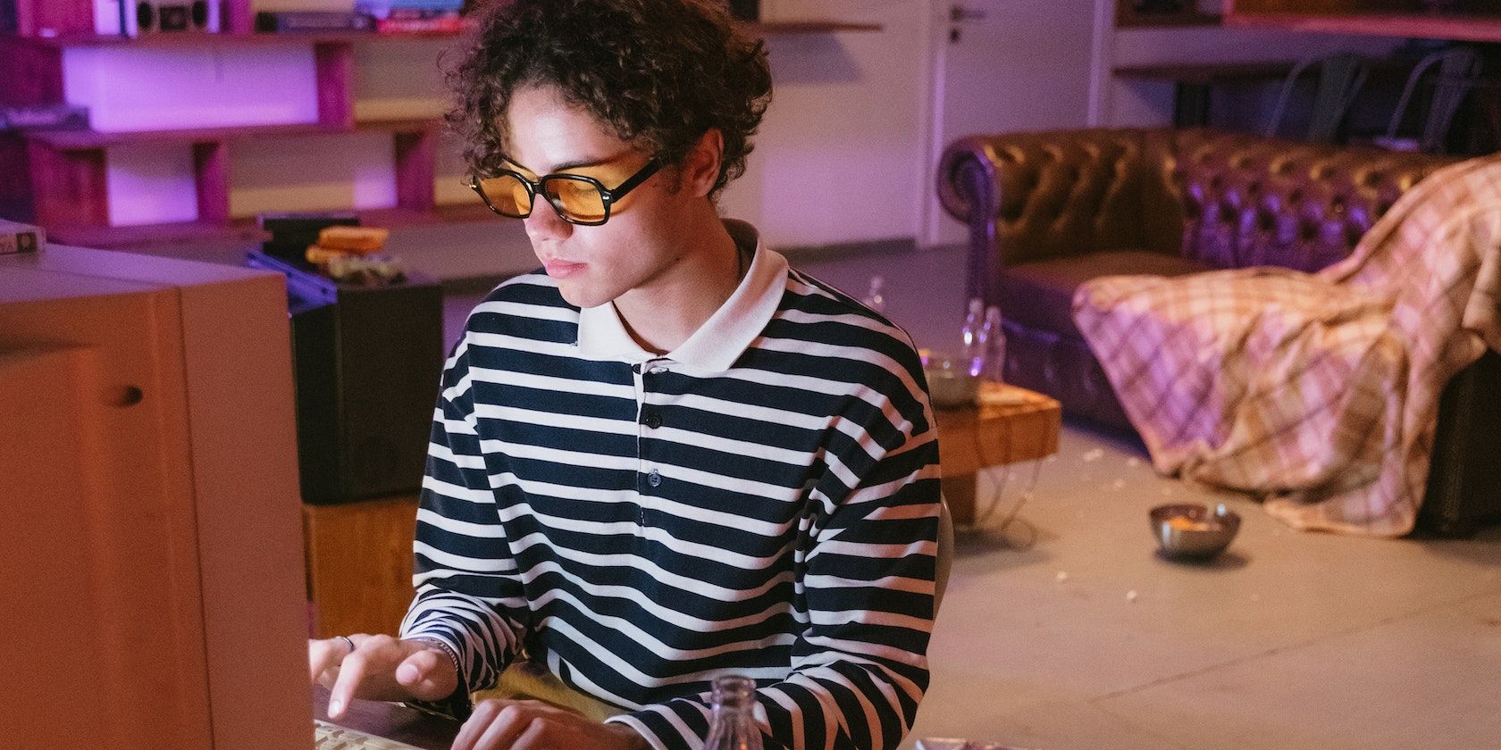 man in black and white striped long sleeve shirt sitting on chair and using a computer