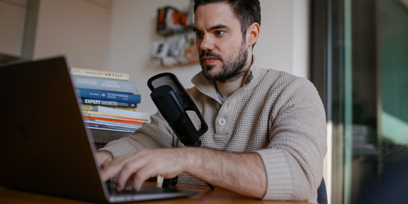 man in gray sweater working on a laptop